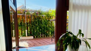 A glass table reflecting an outdoor scene with a wooden deck, potted plants, and a red umbrella. - Apartment 'Abendrot, 45qm' with Lake View, Balcony and Wi-Fi (Sipplingen)