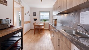 Una cocina moderna con armarios de madera, una mesa de comedor y un lavamanos empotrado.