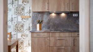 Una cocina con armarios de madera, encimera de mármol y salpicadero con motivos de café.