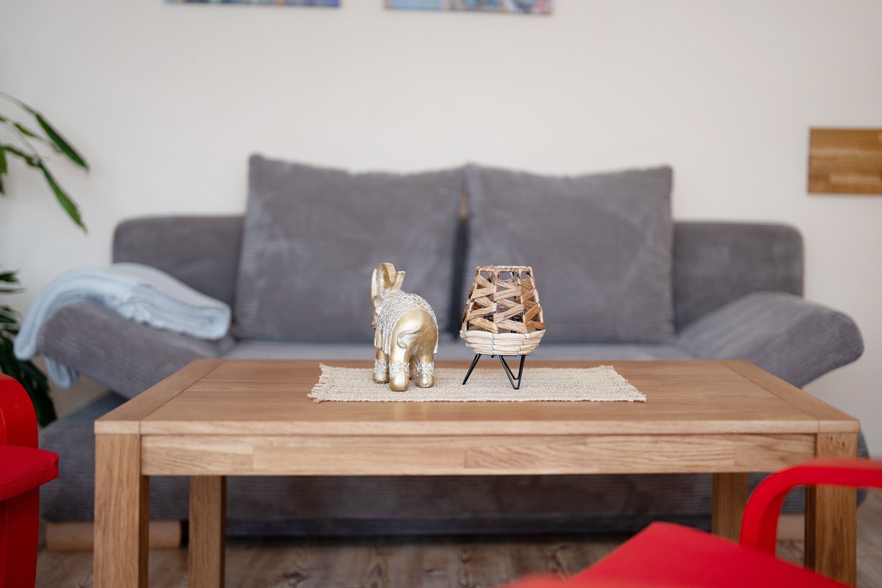 A wooden coffee table with a small figurine and a woven basket on a placemat.