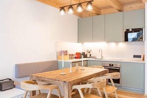 Una cocina moderna con una mesa de comedor de madera, armarios azul claro y un horno empotrado.