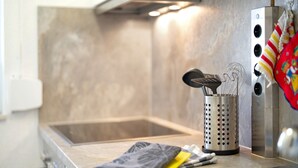 Une cuisine équipée d’un évier en acier inoxydable, d’une passoire et d’une bouilloire.