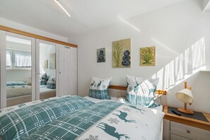 A bedroom with a bed, bedside table, lamp, and artwork on the wall. - Apartment '101 Luisa' with Mountain View, Balcony and Wi-Fi (Schönwald im Schwarzwald)