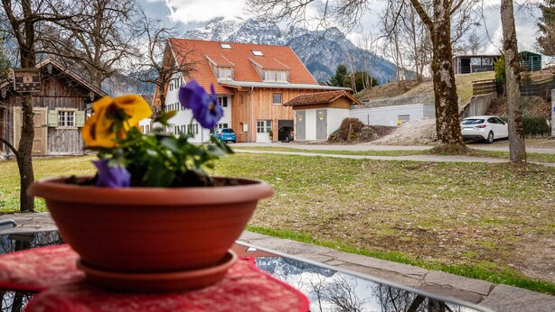 Une maison avec un toit en pente, un garage et une vue sur les montagnes en arrière-plan.