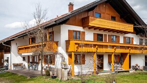 Un bâtiment à deux étages doté d’un balcon, d’une façade en bois et d’un petit porche.