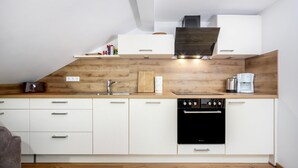 Une cuisine moderne avec des meubles blancs, un four noir et un plan de travail en bois.