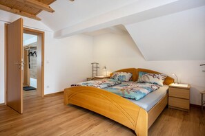 Une chambre à coucher avec un lit en bois, une table de chevet, une lampe et une armoire.