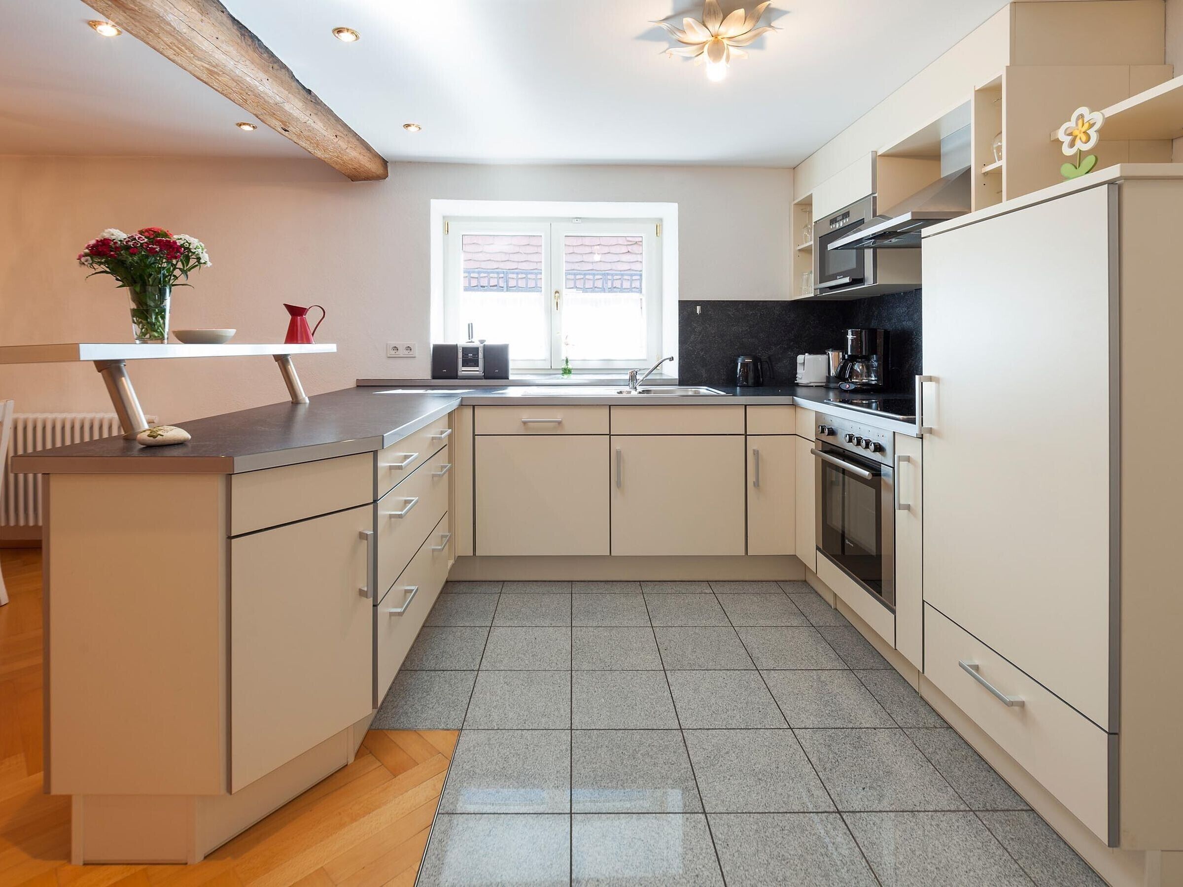 A modern kitchen with a central island, a built-in oven, and a window with a view of a fence.