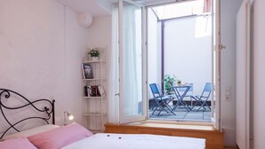 A bedroom with a bed, a bookshelf, and a view of an outdoor patio with a table and chairs. - Apartment 'Kaufmannshaus' with Wi-Fi (Lindau am Bodensee)