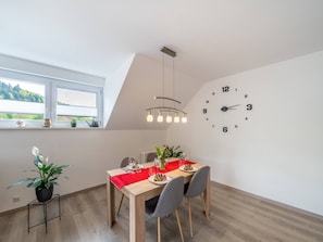 A dining area with a wooden table, red tablecloth, and a wall clock. - Apartment 'Am Spielberg' with Mountain View, Balcony and Wi-Fi (Freiamt)