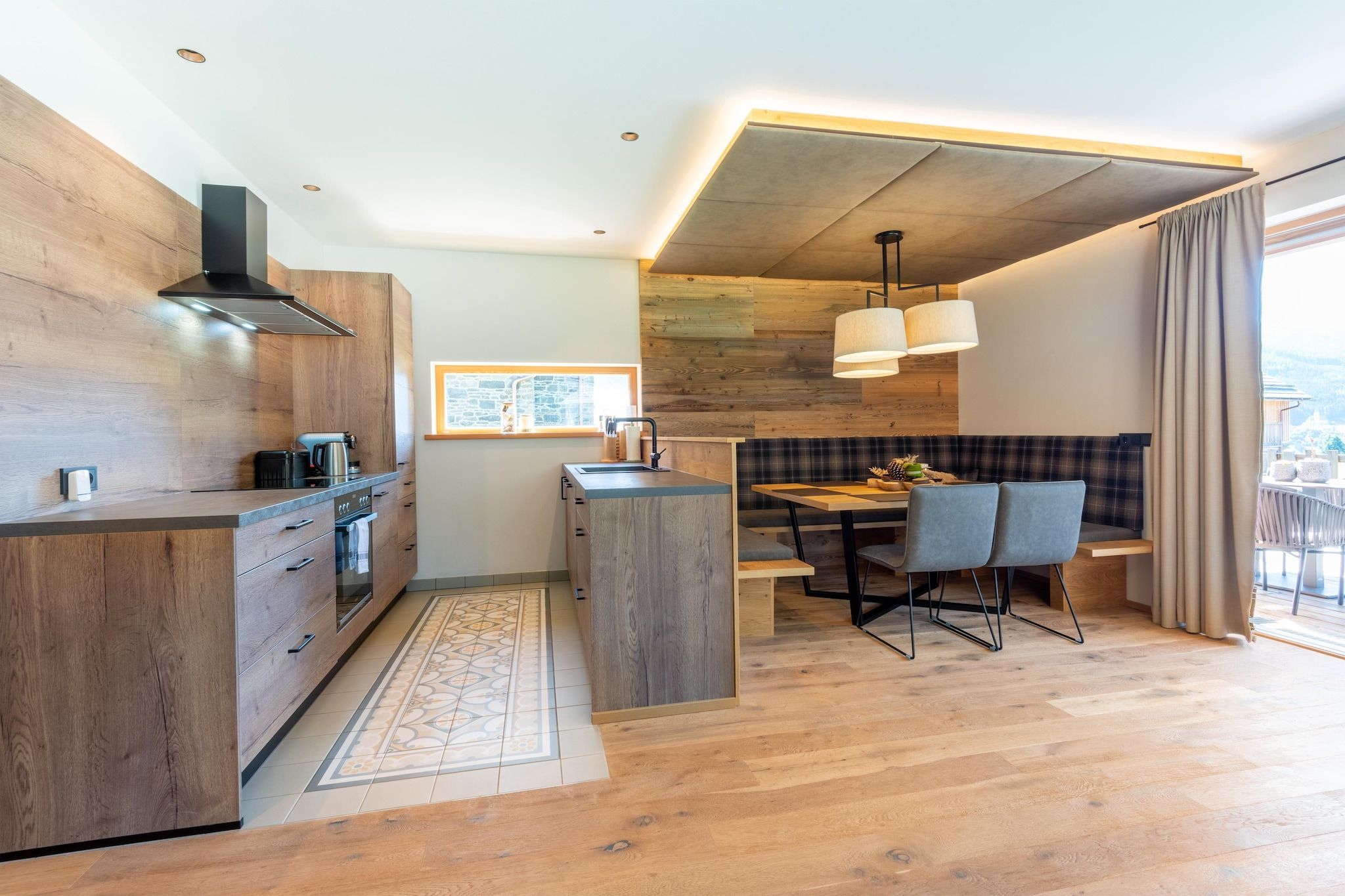 A modern kitchen with wooden cabinetry, a central island, and a dining area with a bench and chairs.