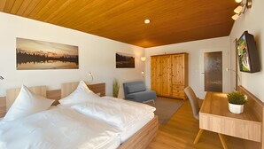Ein Schlafzimmer mit einem Bett, einem Schreibtisch, einem Stuhl, einem Kleiderschrank und zwei Wandbildern.