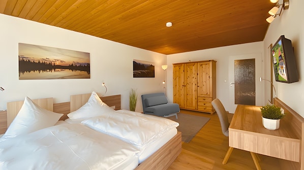 Une chambre à coucher comprenant un lit, un bureau, une chaise, une armoire et deux tableaux accrochés au mur.