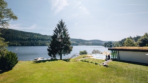 Ein Anwesen am Seeufer mit einem modernen Gebäude, einem Schwimmbad und einer Anlegestelle.