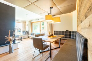 Uma sala de estar moderna com uma mesa de jantar de madeira, um sofá e uma janela grande.