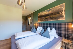 A modern bedroom with a large bed, a headboard with a plaid pattern, and a painting of a landscape on the wall. - Beautiful chalet with sauna in Wölting (Wölting)