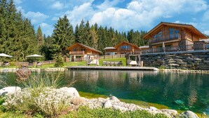 A lakeside lodge with wooden cabins, a stone wall, and a clear view of the lake.