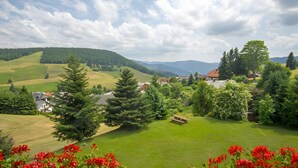 Eine ländliche Landschaft mit sanften Hügeln, einem Dorf und einem markanten Gebäude mit rotem Dach.