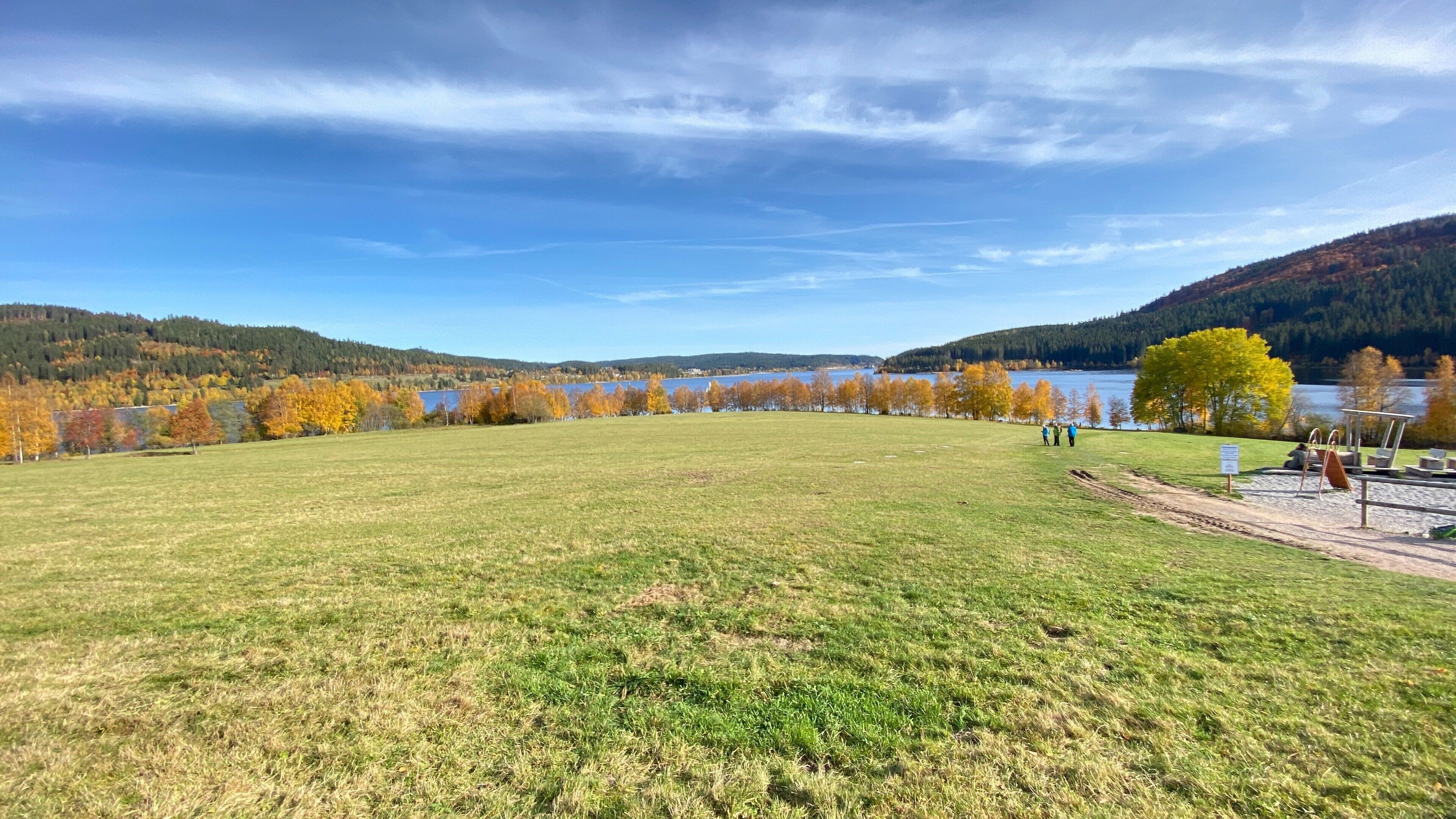 Un champ verdoyant avec un lac et des collines en arrière-plan.