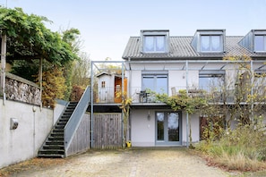 Une maison à deux étages avec un escalier, une porte en bois et une allée pavée.