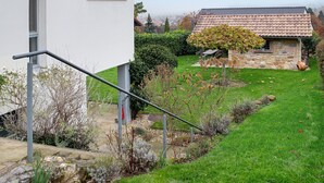 Ein Haus aus Stein mit Ziegeldach, einem Rasen und einer Metalltreppe.