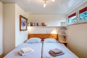 Un dormitorio con dos camas, una estantería, un cuadro enmarcado y un cartel en la pared.
