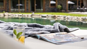 A poolside setting with a towel, a glass of water with a lemon slice, and a magazine.