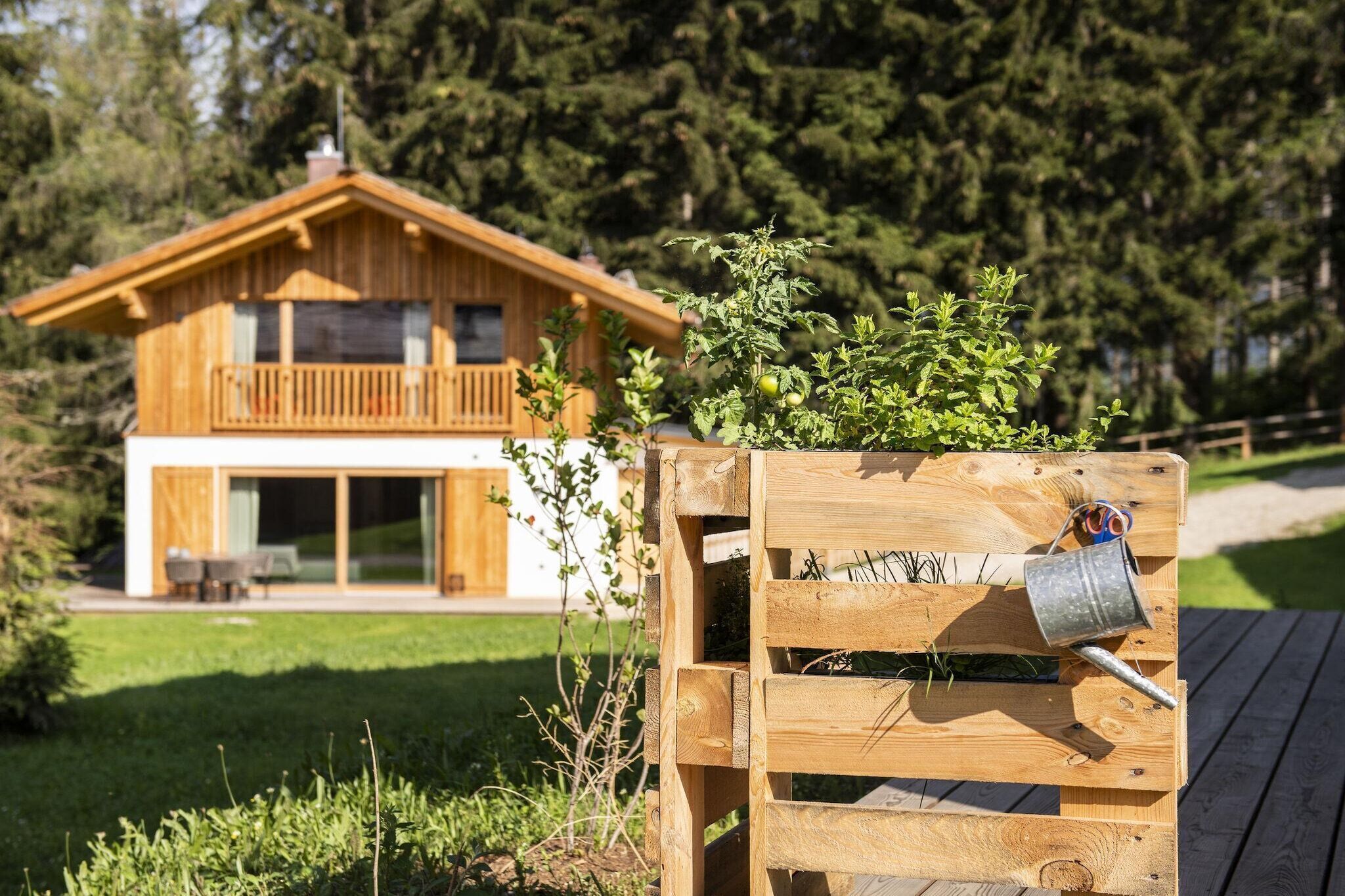 Ein Holzhaus mit Balkon, umgeben von viel Grün und Bäumen.