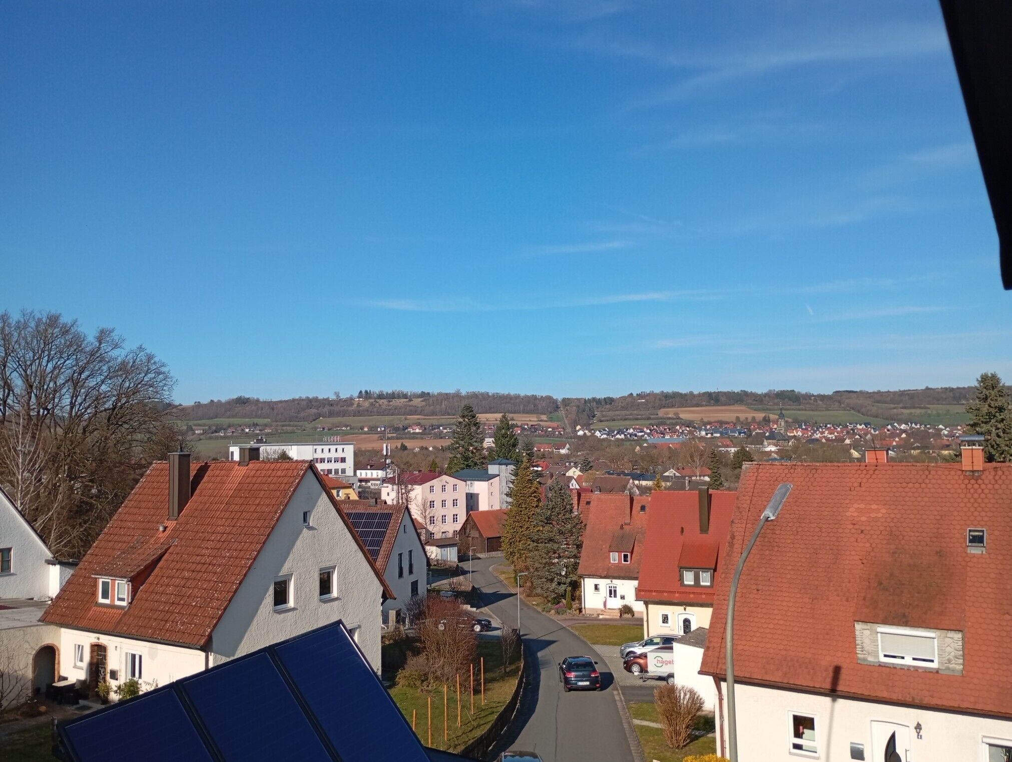 A residential area with houses, a clear sky, and a distant view of a town.