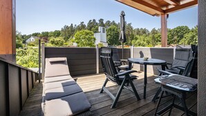 A covered outdoor deck with a sofa, chairs, and a grill.