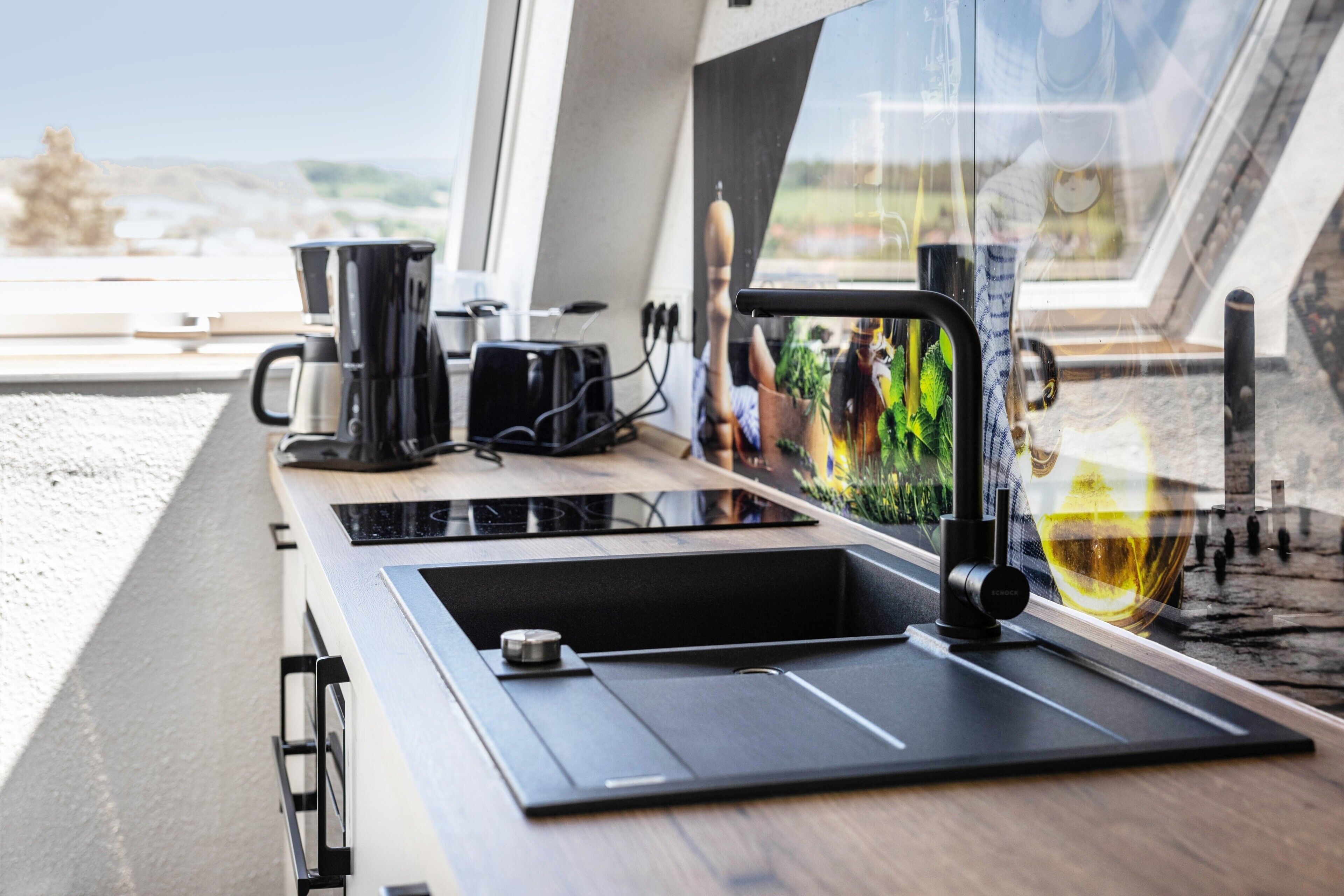 Una cucina moderna con piano cottura integrato, una macchina per caffè e un lavandino.