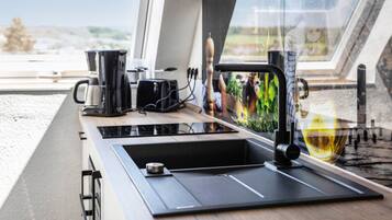 Una cucina moderna con piano cottura integrato, una macchina per caffè e un lavandino.