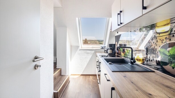 A modern kitchen with a view of the countryside, a wooden countertop, and a skylight.
