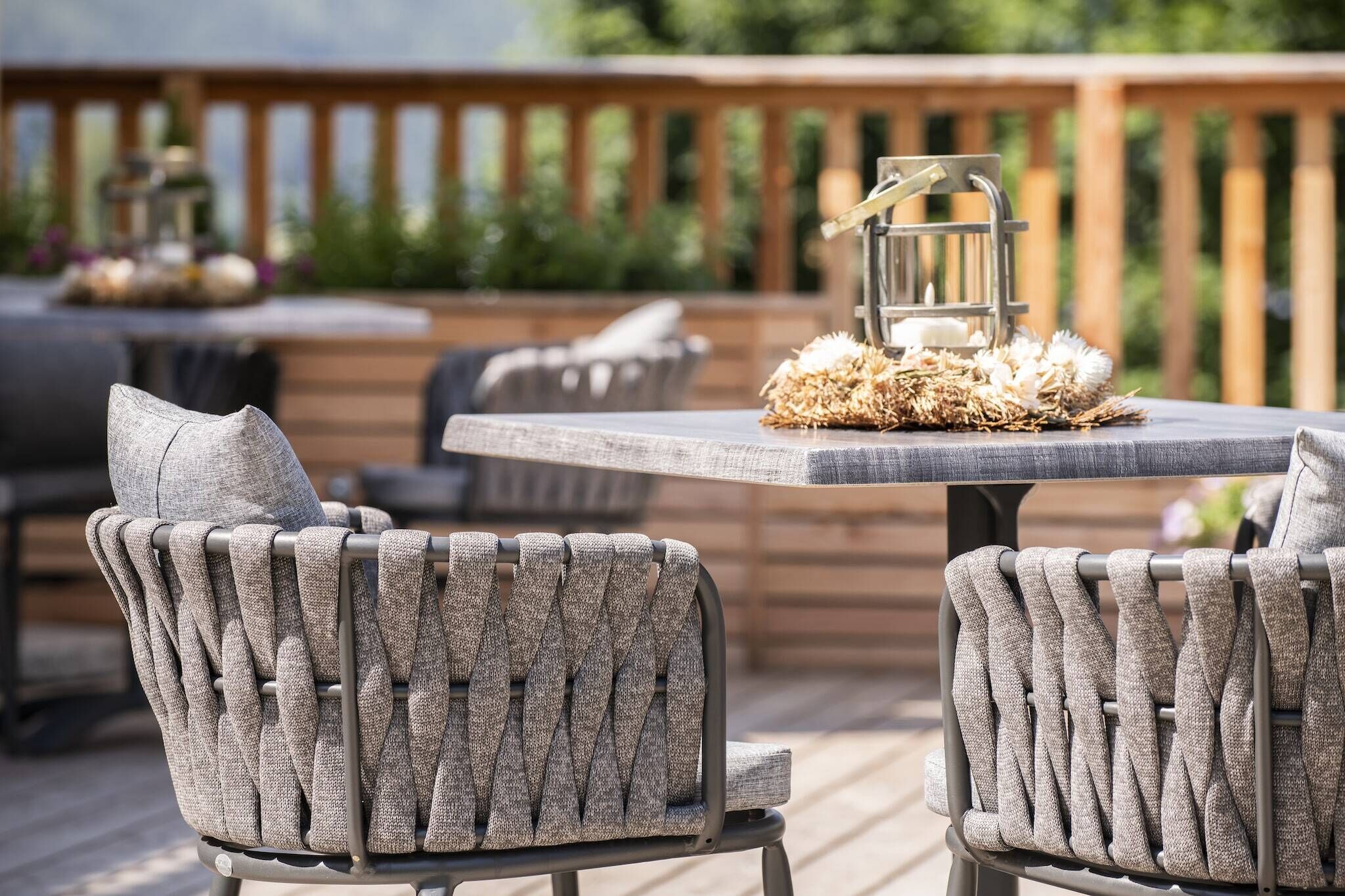 Una terraza con mobiliario exterior, que incluye una mesa y sillas, y un centro decorativo.