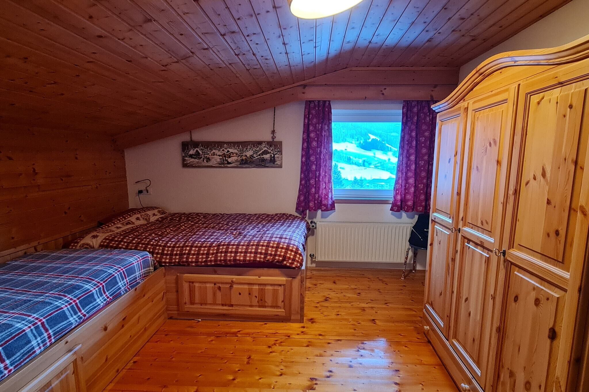 Una habitación de madera con techo inclinado, una cama con manta de cuadros, un radiador y un armario.