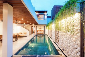 Una casa moderna con piscina, una escalera y un balcón con plantas.