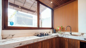 A modern kitchen with a large window, wooden cabinetry, and a marble countertop. - Villa Casanaya Pererenan Canggu (Canggu)
