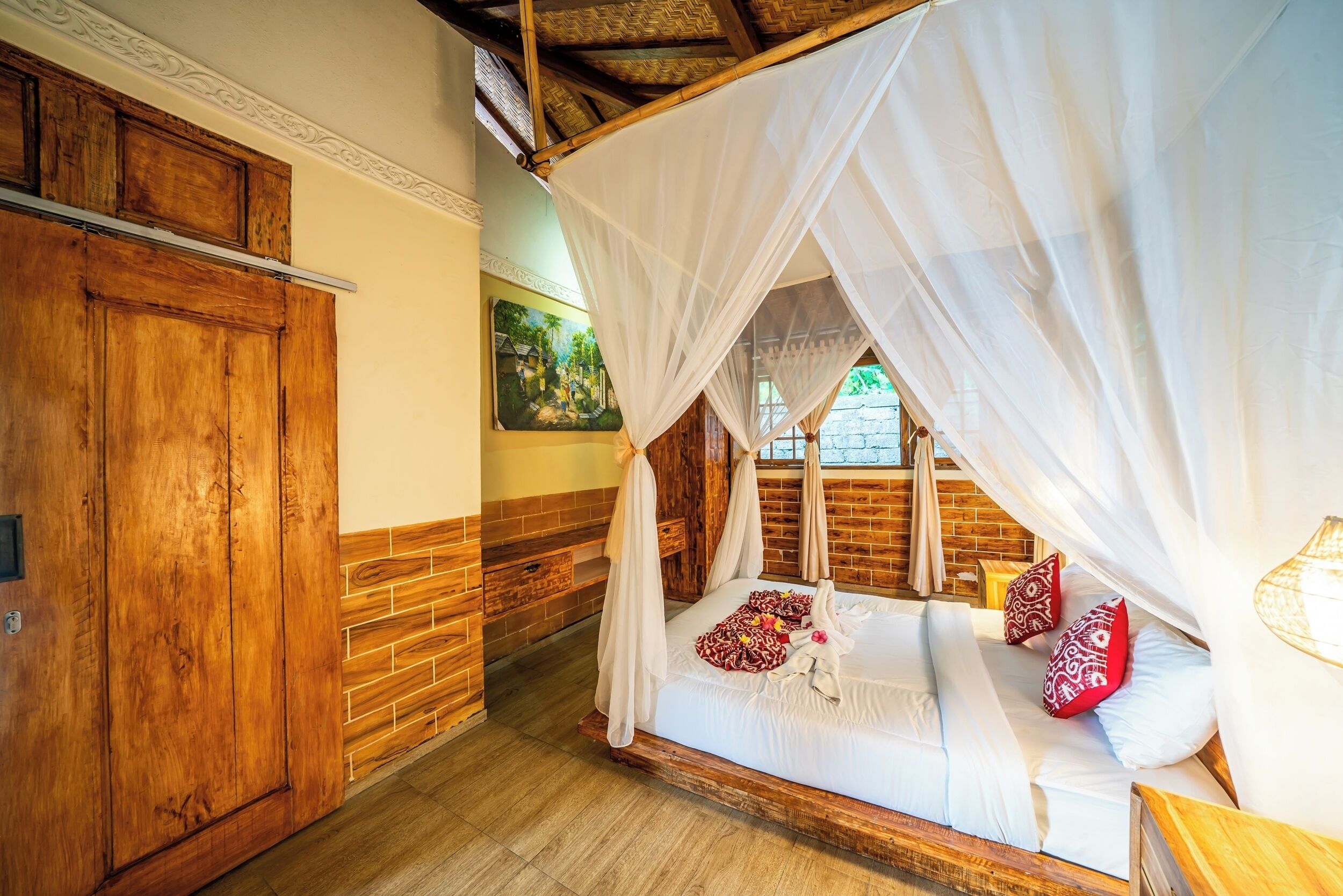 A room with a wooden bed, white canopy, and a brick wall.