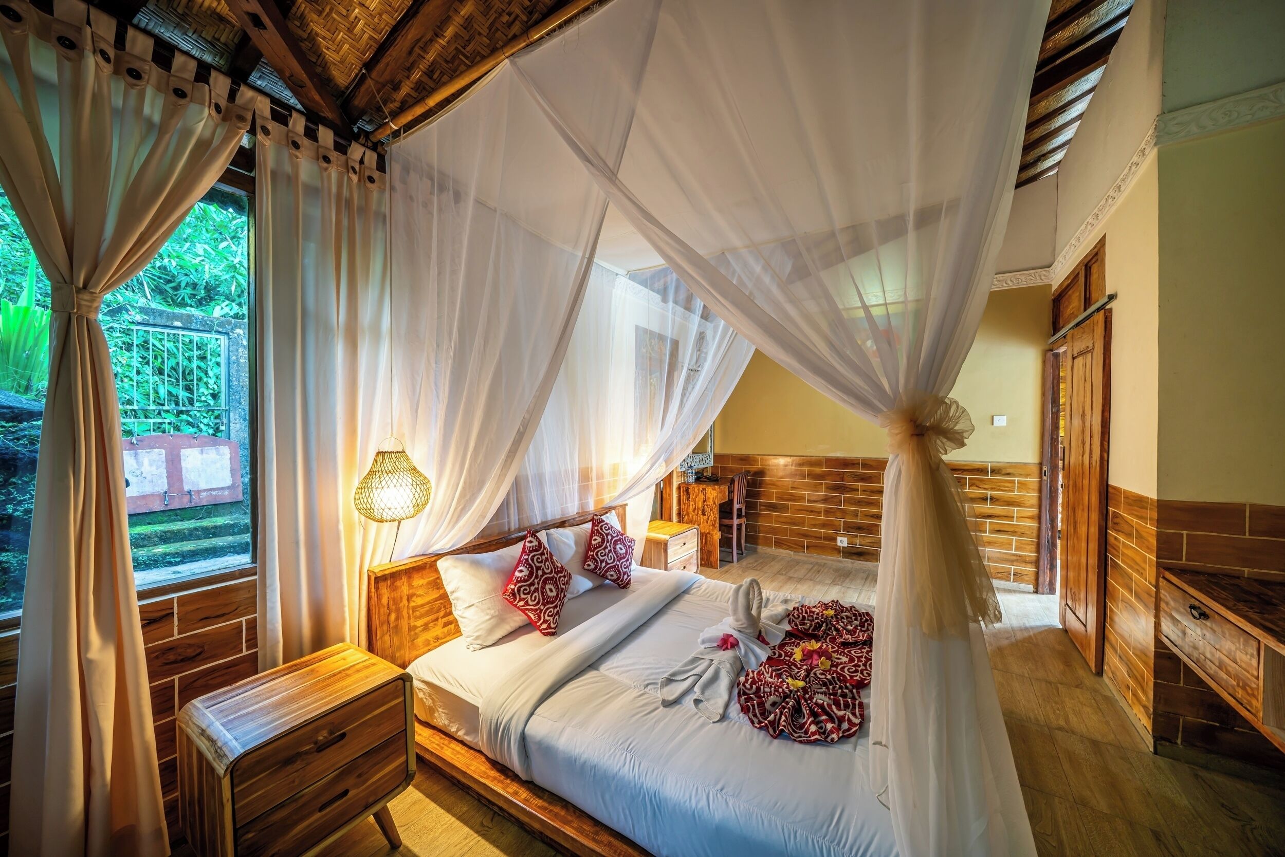 Un dormitorio con cama, mesita de noche y ventana con cortinas.