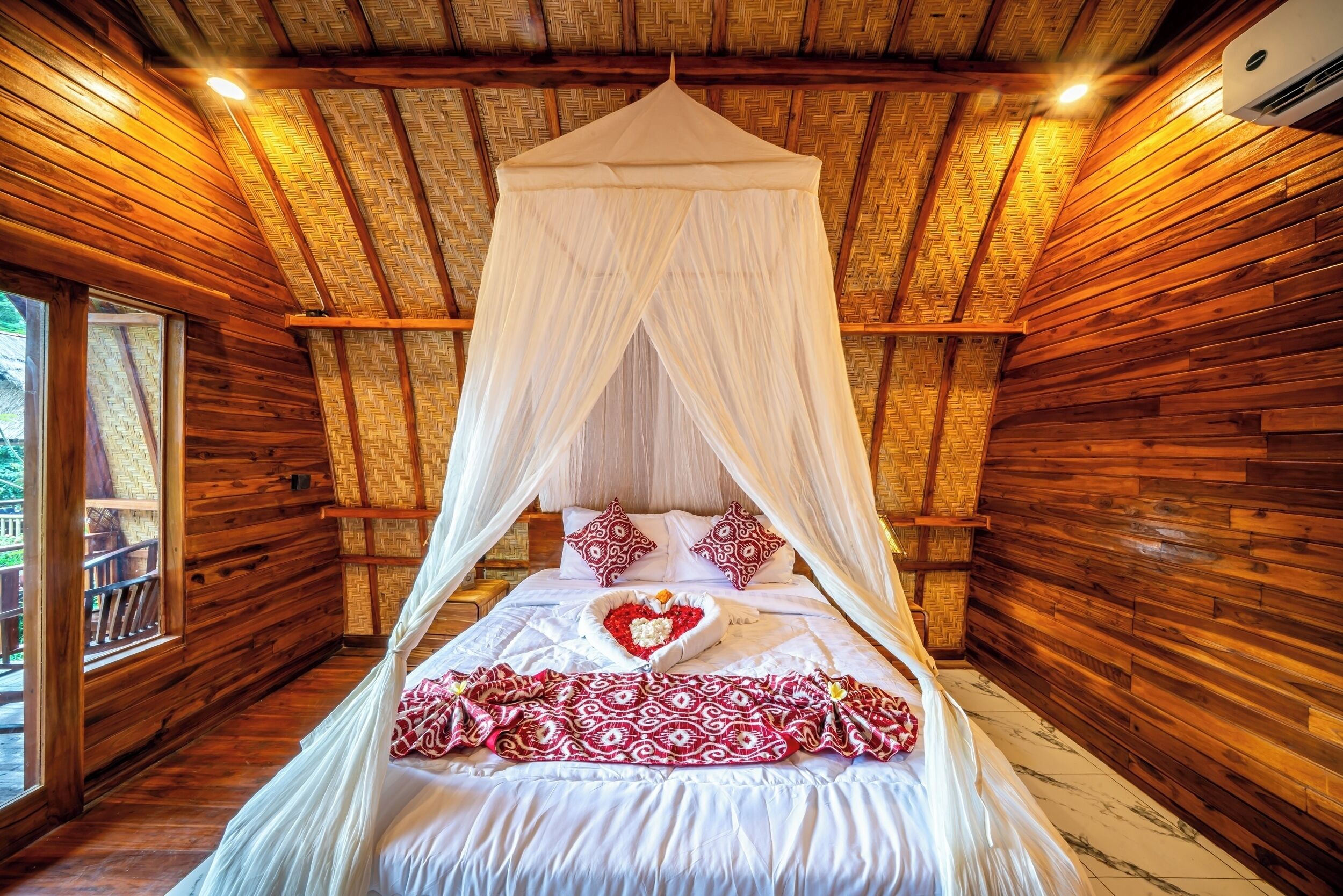 A wooden room with a bed under a canopy, a window, and a wooden ceiling.