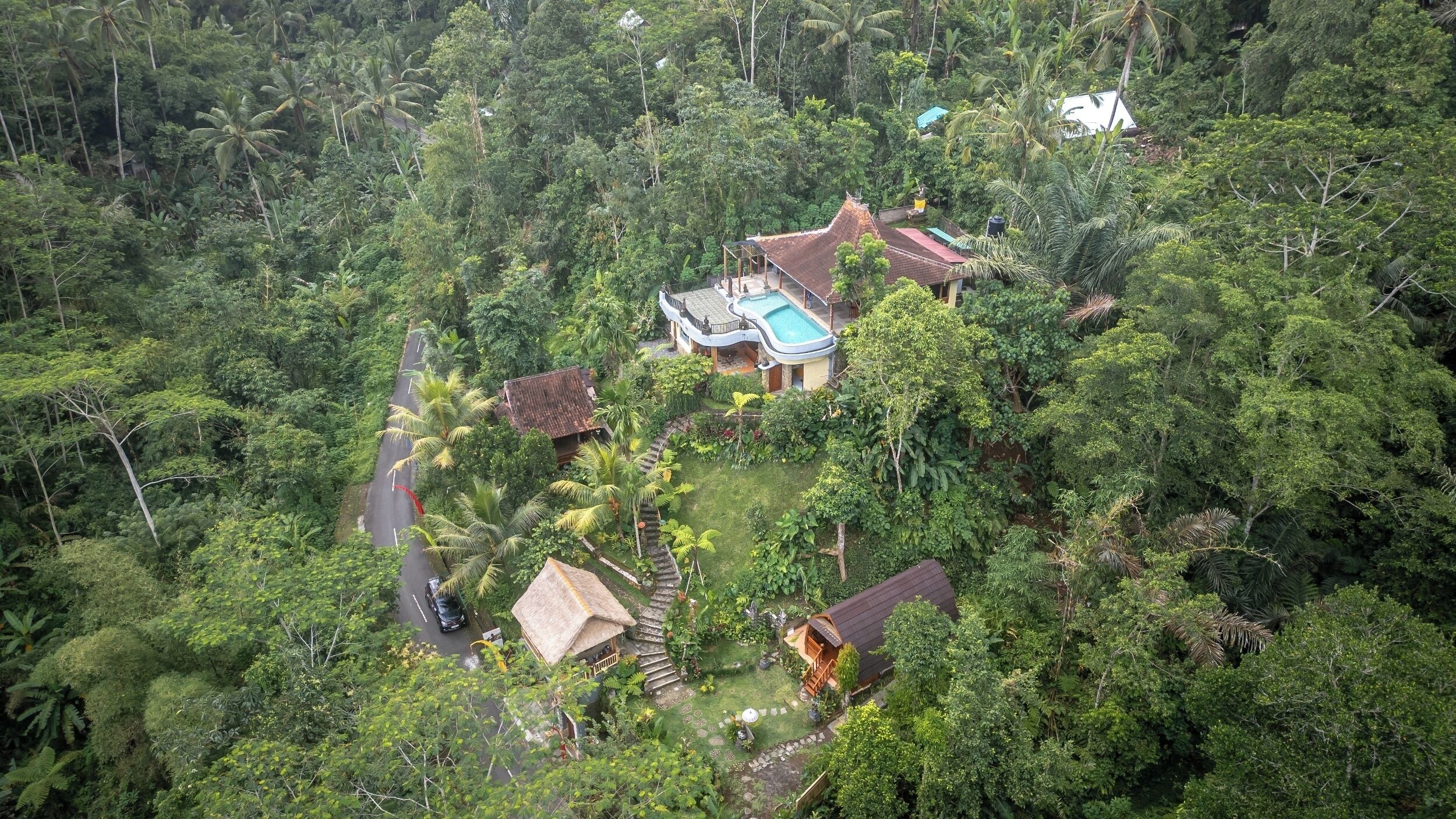 Un resort tropical con piscina, varias construcciones y abundante vegetación.