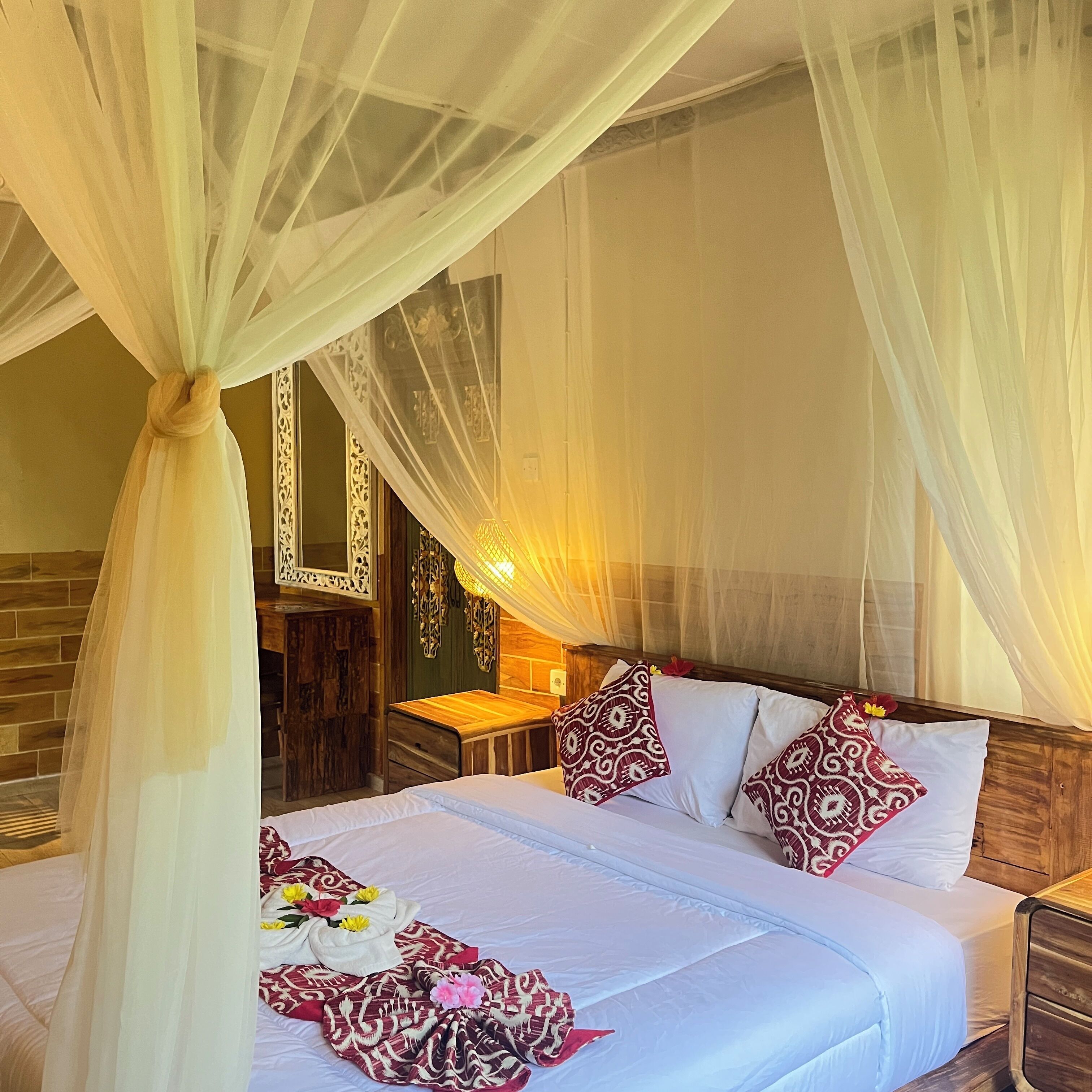 A hotel room with a bed, a wooden headboard, a nightstand, a mirror, and a decorative wall panel.