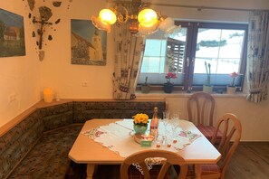 A dining area with a table set for two, a chandelier, and a window with a view of a building. - Alpine Holiday Home in Lungau (Vordermuhr)