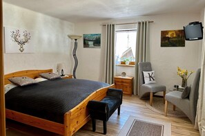 A bedroom with a wooden bed, a bench, a chair, a small table, and a TV. - Alpine Holiday Home in Lungau (Vordermuhr)