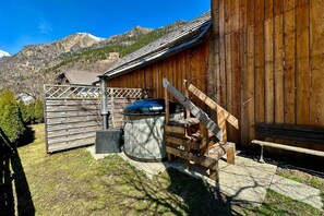 A wooden building with a metal barrel, a wooden bench, and a wooden fence. - Alpine Holiday Home in Lungau (Vordermuhr)