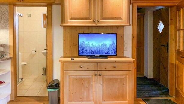 A wooden cabinet with a television on top, a trash bin, and a door leading to another room. - Chalet in Königsleiten near Ski Slopes (Königsleiten)