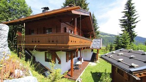 A chalet with a wooden balcony, a small deck, and a view of the surrounding mountains. - Chalet in Königsleiten near Ski Slopes (Königsleiten)