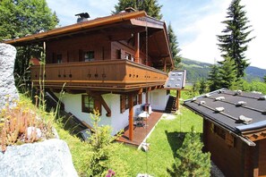 A chalet with a wooden balcony, a small deck, and a view of the surrounding mountains. - Chalet in Königsleiten near Ski Slopes (Königsleiten)
