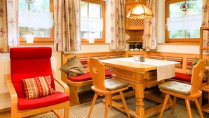 A cozy room with a wooden dining table, red upholstered chairs, and a red armchair with patterned cushions. - Chalet in Königsleiten near Ski Slopes (Königsleiten)
