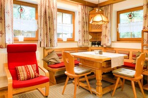 A cozy room with a wooden dining table, red upholstered chairs, and a red armchair with patterned cushions. - Chalet in Königsleiten near Ski Slopes (Königsleiten)